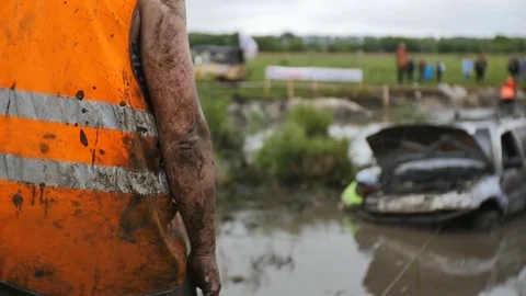 Back of driver in orange dress looking at stucked car in mud and dirt Video stock 77429596