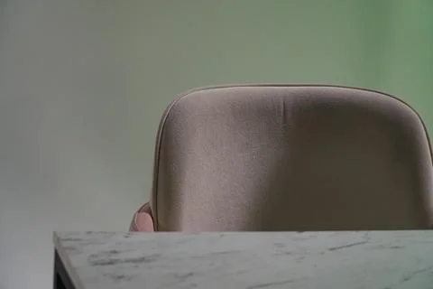 Back of an empty chair with soft pile cover, next to a blurred table surfac.. Stock Photos