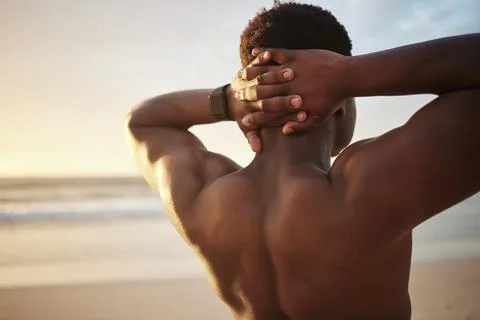 Back of a fit muscle man with hands behind his head, at the beach looking at the Stock Photos