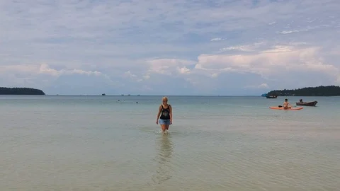 Back flying drone footage from the front side of a girl walking in the sea towar Stock Footage 111395999
