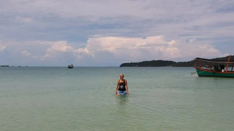 Back flying drone footage from the front side of a girl walking in the sea  Stock Footage 111396026