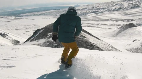 From the back following snowboarder riding down the slope on deep fresh snow Stock Footage 144335443