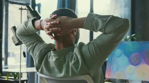 Back footage of office worker with hands behind back sitting at workplace in Stock Footage 214010044