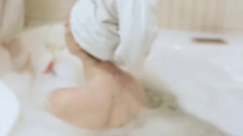Back of a girl in a foam bath that drinks champagne from a glass Stock Footage 114317613