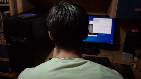 Back of head young guy with black hair sitting computer, moves his hand, mouse Stock Footage 121537400