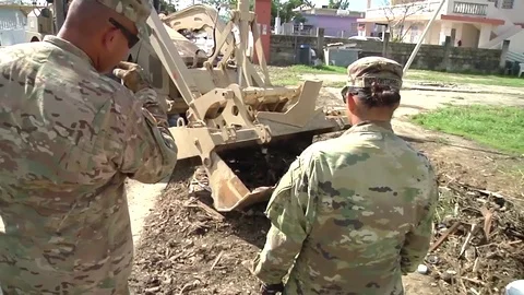 Back hoe machine clearing earth with bucket left by Hurricane Maria 動画素材 82789928