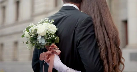 Back, hug and couple with flower bouquet for wedding, commitment ceremony and 動画素材 289966580
