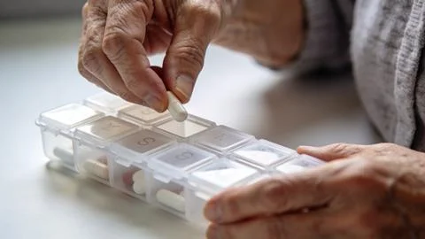 Back left view old person hands taking pills Фото