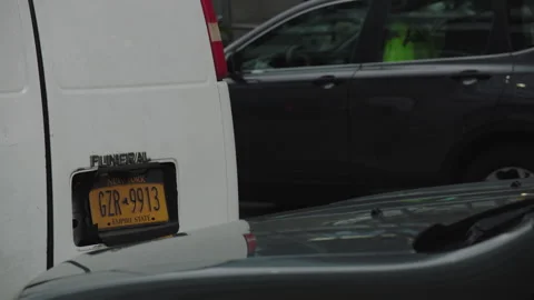Back license plate view of white funeral van at covid testing site in nyc Stock Footage 251198923