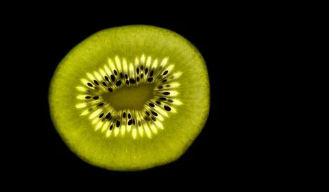 Back light isolated slice macro photo of a kiwi slice isolated on black col.. Stock Photos