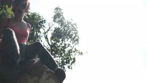 Back lit female climber try to find a way down on cliff Stock Footage 136643895