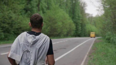 Back look of a young man in hood running on the road near the forest 4K Stockbeeldmateriaal 75543381
