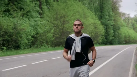 Back look of a young man in hood running on the road near the forest 4K 스톡 동영상 75543907