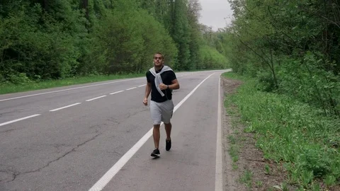 Back look of a young man in hood running on the road near the forest 4K 스톡 동영상 75544595