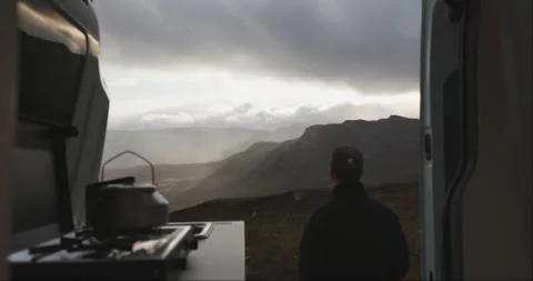 Back of male standing outside open campervan door with Jotunheimen sunset Stock Footage 255203484