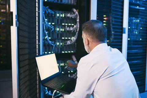 Back, man and mainframe with laptop in server room for programming, coding and Stock-Fotos