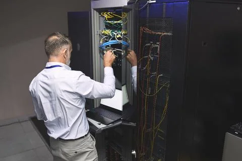 Back, man and programmer with laptop in server room for programming, coding and Stock-Fotos