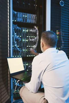 Back, man and programming with laptop in server room for research, coding and Stock-Fotos