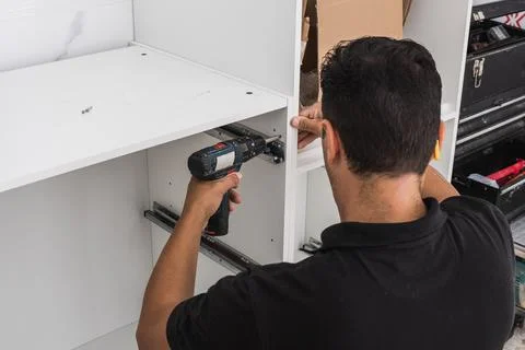 Back of a man assembling a kitchen with a drill Stock Photos