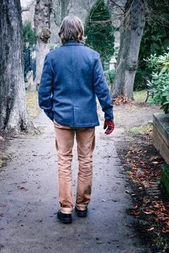 Back of man in jacket walking outside in a park Stock Photos