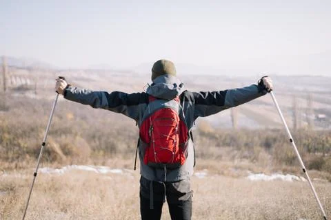 Back of man wearing backpack and hiking poles Stock Photos