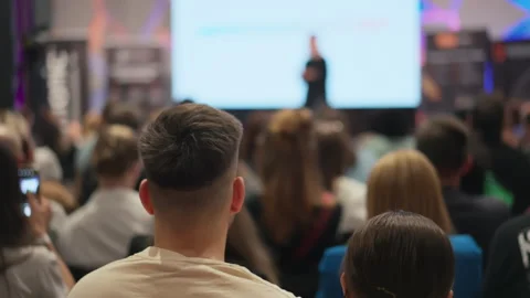 Back of a man's head in the foreground at a lecture. Engrossed young adults Stock Footage 273485984