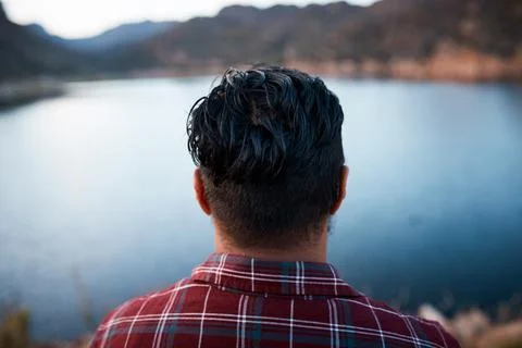 The back of a man's head while he admires the lake view on camping mountain trip Stock Photos