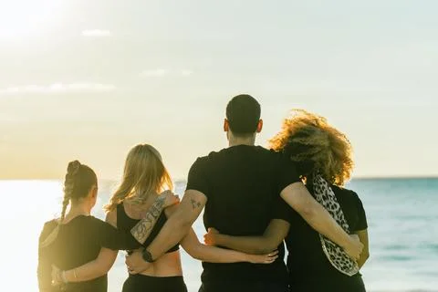 Back of a multiethnic yoga class group embracing for the back facing the sea Stock Photos