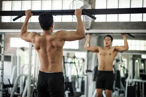 Back muscle building by pulling bar in gym Stock Photos
