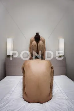The back of a naked man in a crouched position and the front of a naked woman in Stock Photos