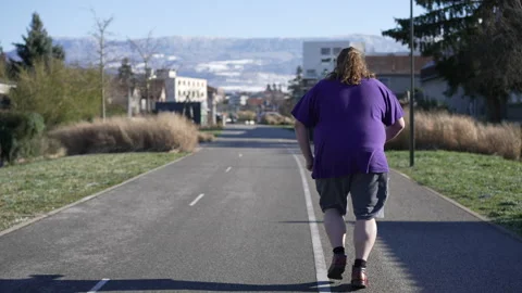 Back of One young overweight man jogging outdoors. Tracking shot of a chubb.. Stock Footage 231415634