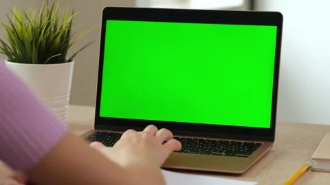 Back over shoulder view of young girl doing homework on laptop with green screen Stock-Footage 319113370