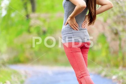 Back pain - Athletic running woman with back injury Stock Photos