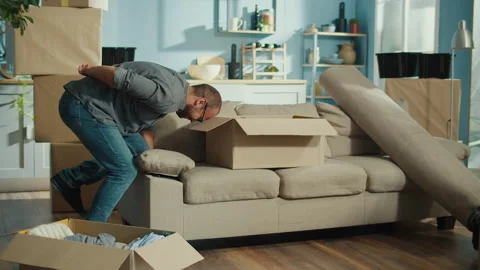Back Pain from Lifting During Move: Man Strains Back While Unpacking Boxes Stock Footage 311581678