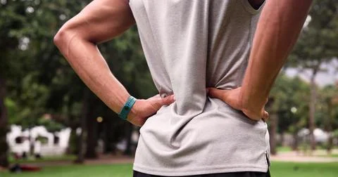 Back pain, runner and hands of man in nature for training fatigue, athlete Stock Photos