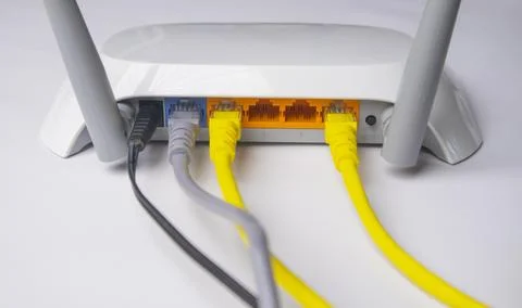 Back panel view of a white wireless router with one black power cable, one .. Stock Photos