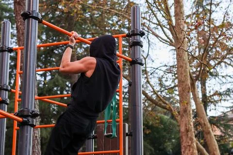 Back perspective of man on outdoor pull-up bars in park Fotos de archivo