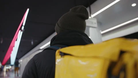 Back of a pizza deliveryman with a yellow backpack who goes up to the metro Stock Footage 236089670