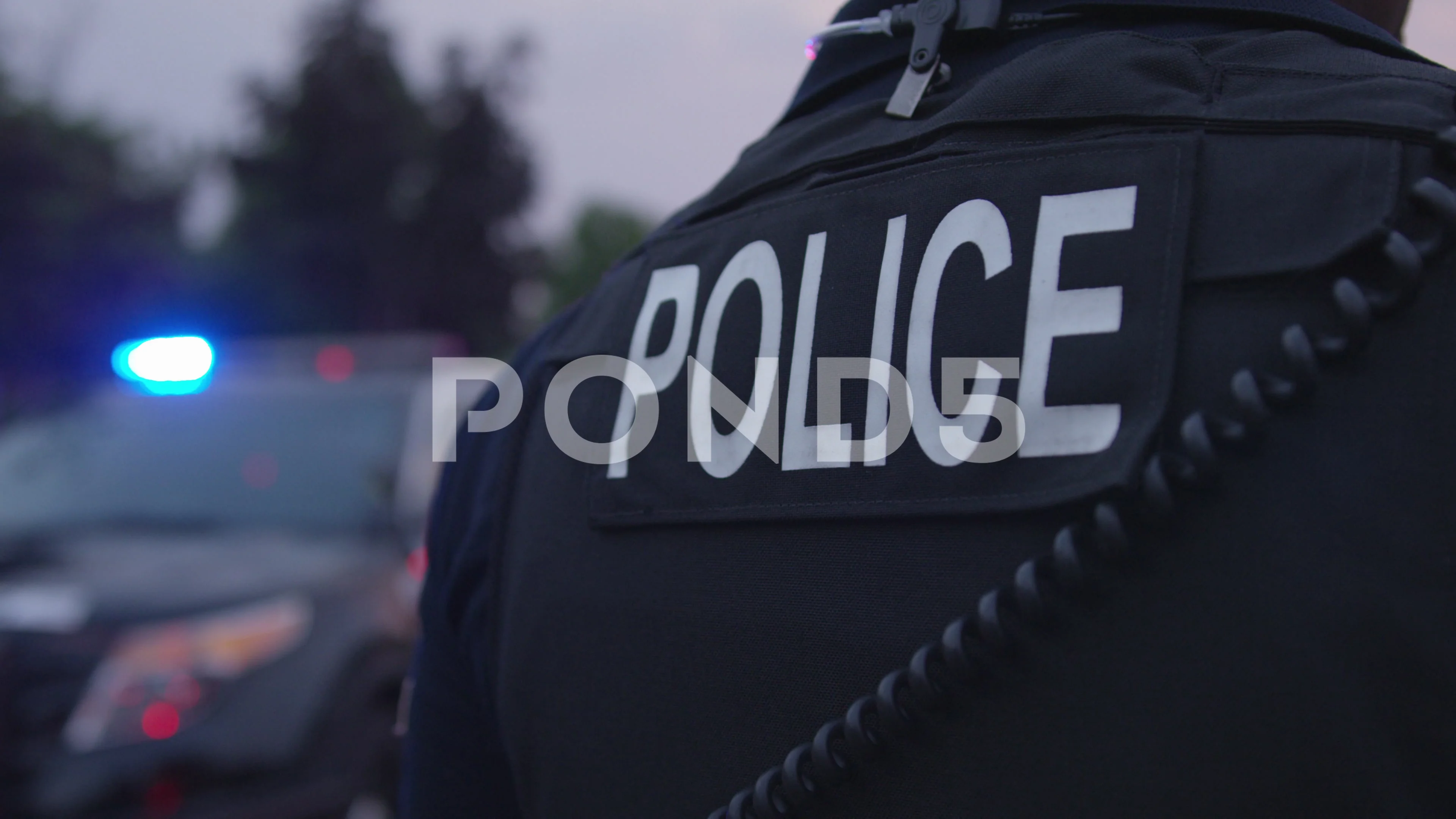 The back of a uniform Police Officer by a Police vehicle on the