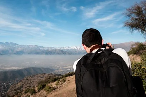 Back portrait of young man taking photos of mountain scenery Stock Photos