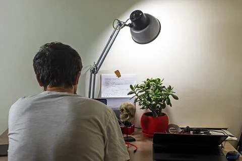 Back programmer is coding at the computer at home at his desktop with a flo.. Stock Photos