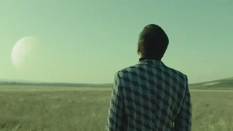 Back rear view of lonely man walking on field .  Approach of two nearby planets Stock Footage 218619374
