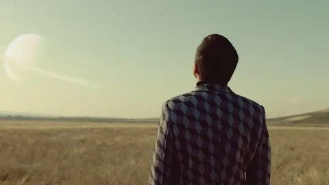 Back rear view of lonely man walking on field .  Approach of two nearby planets Stock Footage 218619413