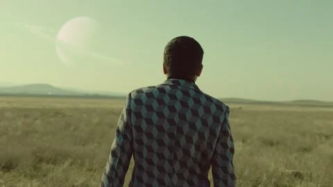 Back rear view of lonely man walking on field .  Approach of two nearby planets Stock Footage 218619700