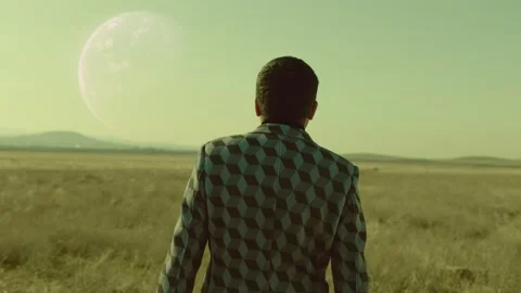 Back rear view of lonely man walking on field .  Approach of two nearby planets Stock Footage 218619726
