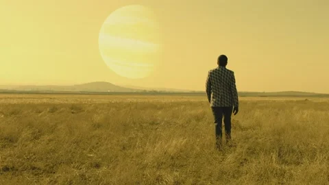 Back rear view of lonely man walking on field .  Approach of two nearby planets Stock Footage 218619856