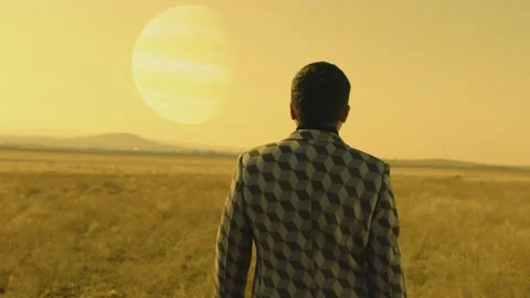 Back rear view of lonely man walking on field .  Approach of two nearby planets Stock Footage 218619872