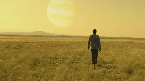 Back rear view of lonely man walking on field .  Approach of two nearby planets Stock Footage 218620032