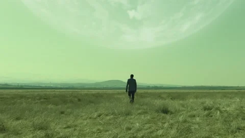 Back rear view of lonely man walking on field .  Approach of two nearby planets Stock Footage 218626753