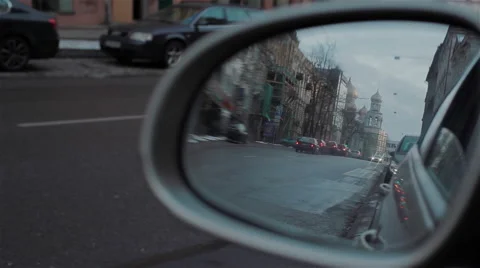 Back road reflected in car mirror, evening street with buildings and moving cars Stock Footage 46368006